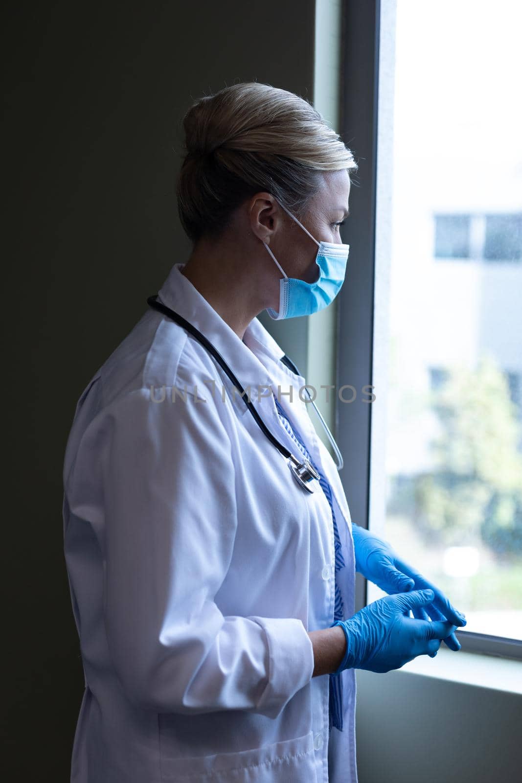 Portrait of caucasian female doctor wearing mask and latex gloves looking ahead by Wavebreakmedia