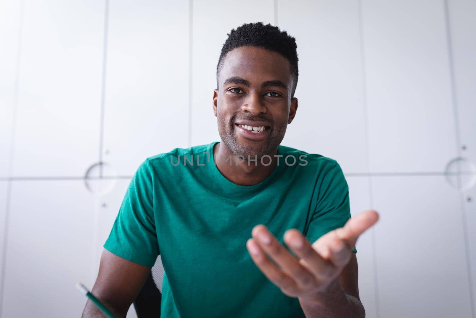 African american businessman sitting in office having video call and making notes. independent creative design business.