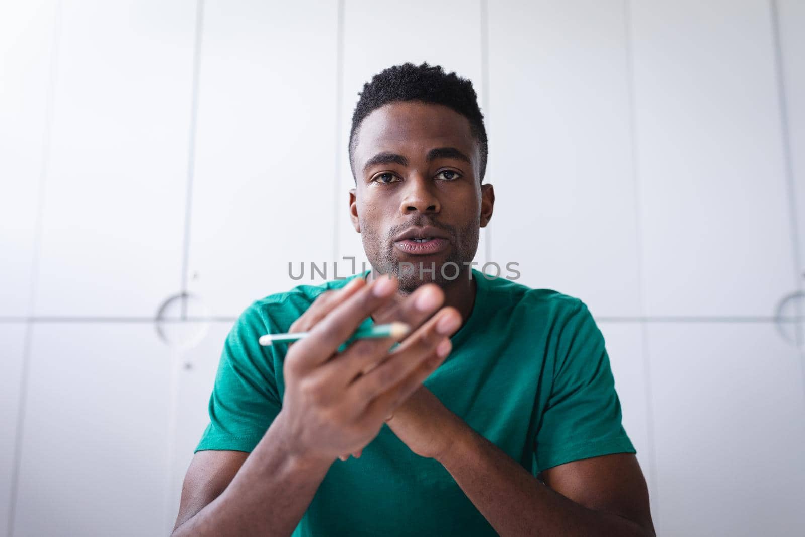 African american businessman sitting in office having video call and making notes by Wavebreakmedia