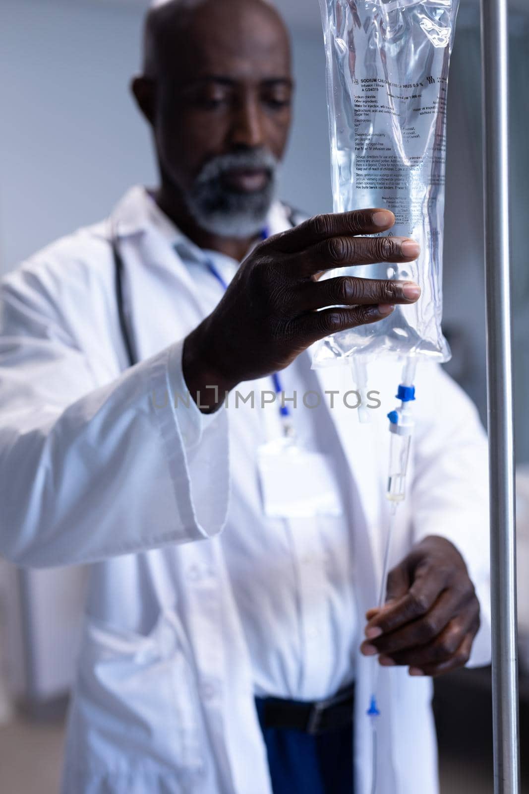 African american male doctor preparing iv drip bag on stand in hospital ward by Wavebreakmedia