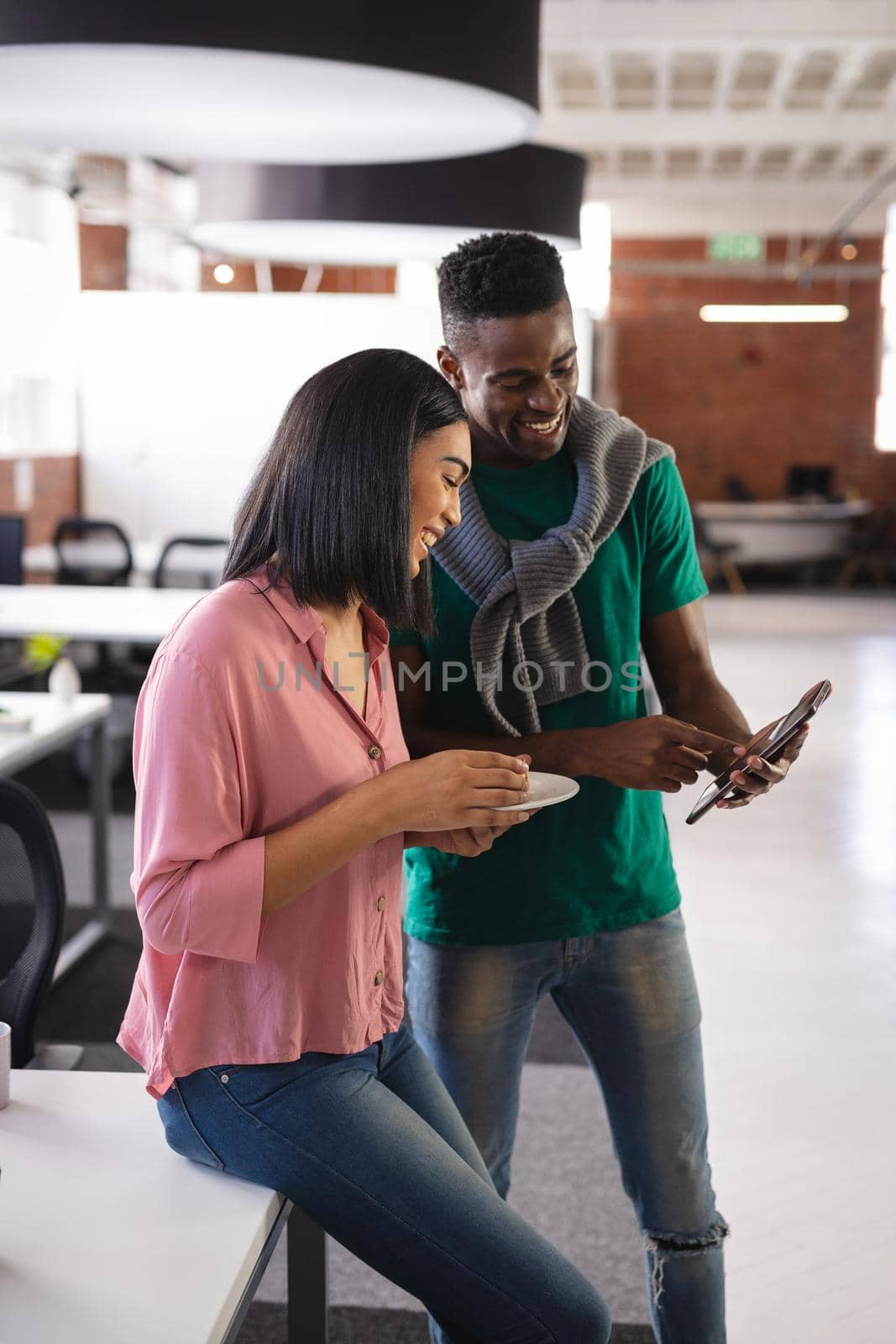 Happy diverse business colleagues having snack in office looking at smartphone by Wavebreakmedia