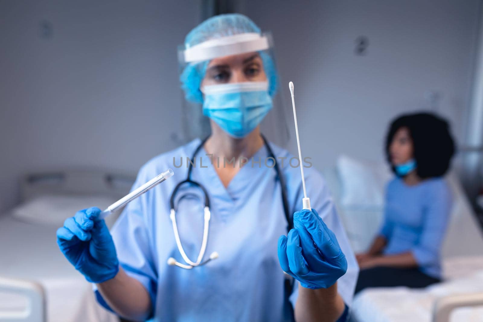 Caucasian female doctor in hospital wearing face mask and surgical gloves holding swab test by Wavebreakmedia