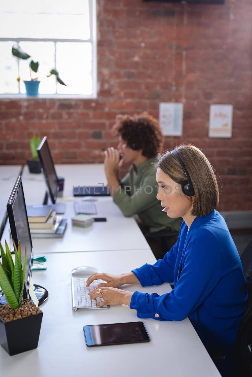 Asian businesswoman sitting in front of computer wearing headset having video call. independent creative design business.