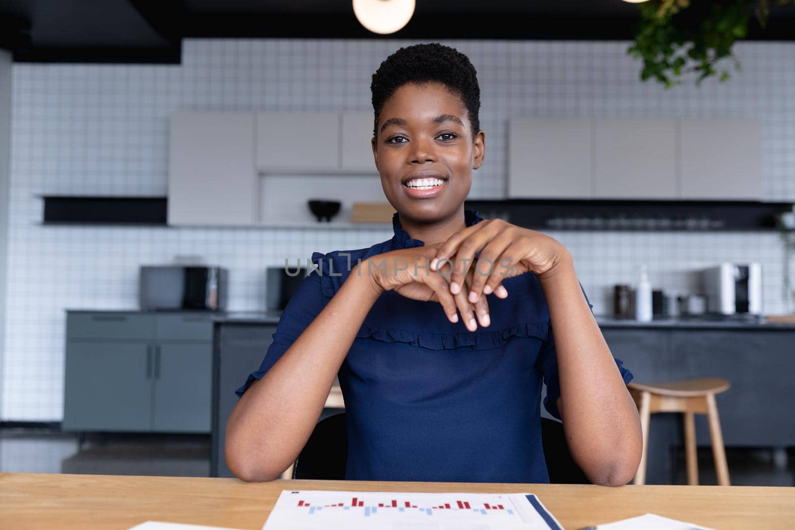 Mixed race businesswoman sitting having video chat going through paperwork in modern office by Wavebreakmedia