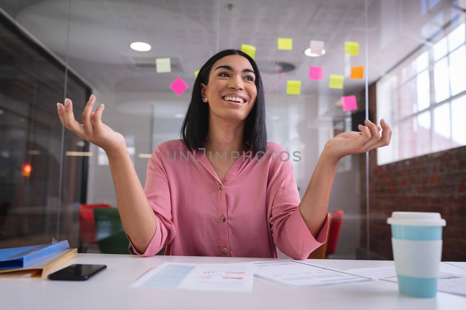 Happy mixed race businesswoman sitting at desk while having a video call smiling. independent creative design business.