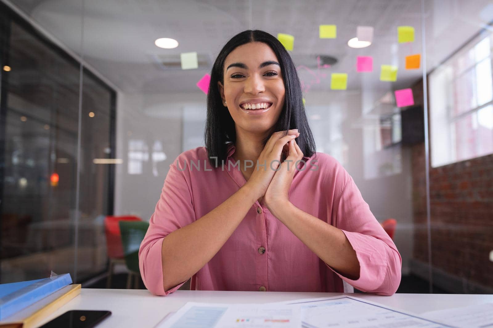 Happy mixed race businesswoman sitting at desk while having a video call smiling. independent creative design business.