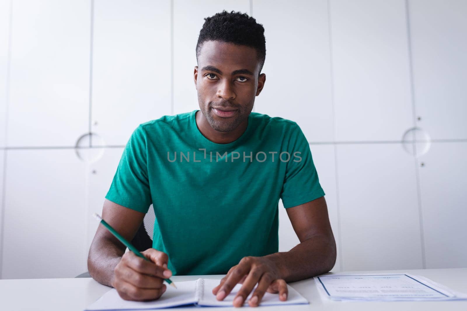 Happy african americen businessman sitting at desk while having a video call making notes. independent creative design business.