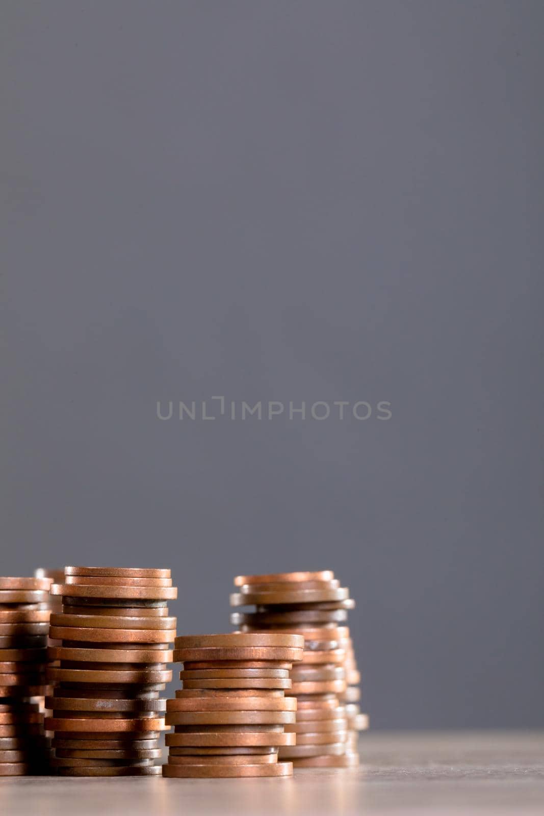 Close up of stack of coins on wooden table against grey background. finance and investment concept