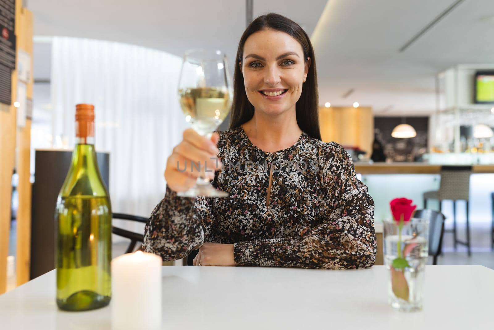 Caucasian woman sitting at table in restaurant on dinner date smiling holding wine glass. friends talking to each other sitting in a restaurant.