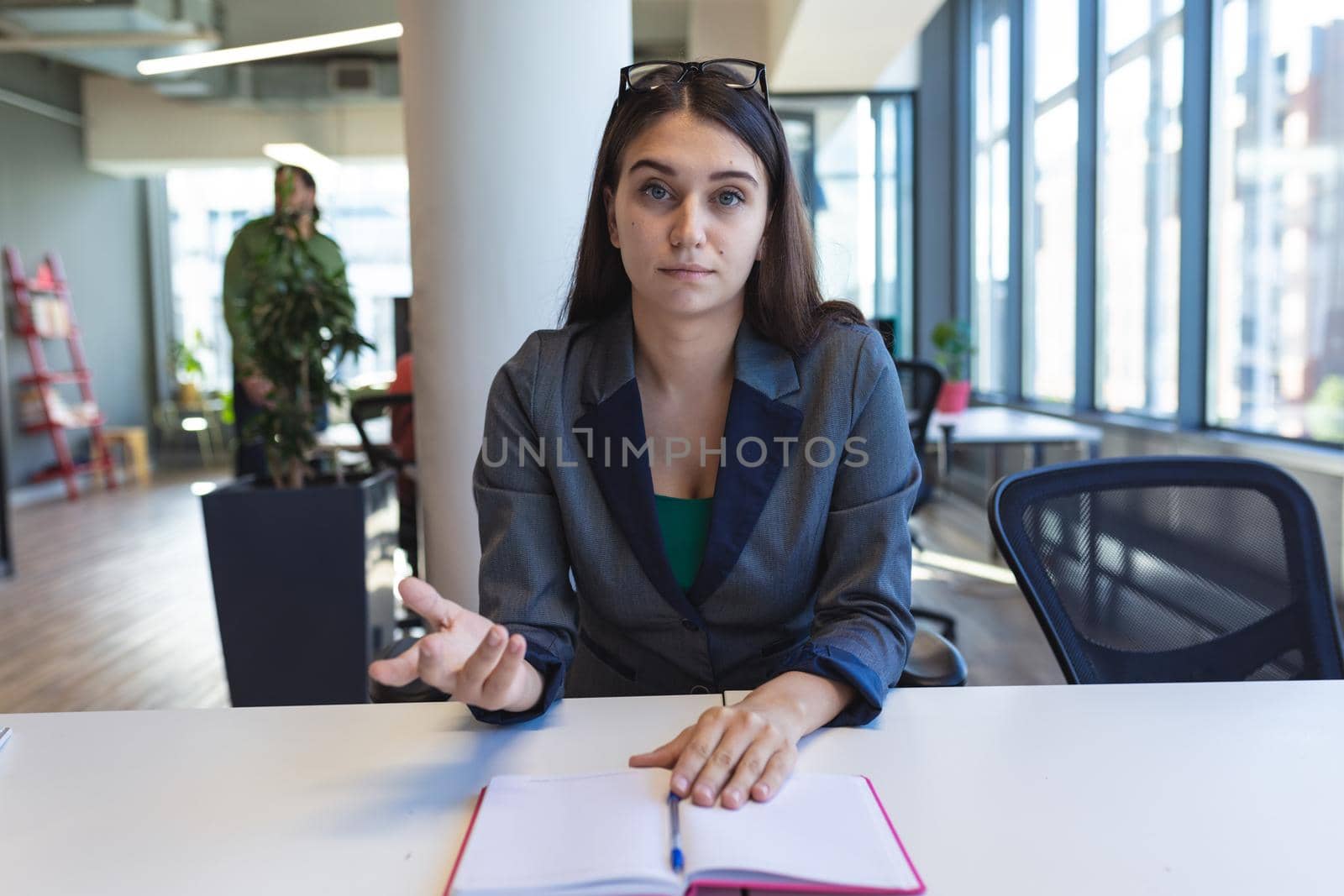 Portrait of caucasian female creative worker sitting at desk looking at camera. modern office of a creative design business.