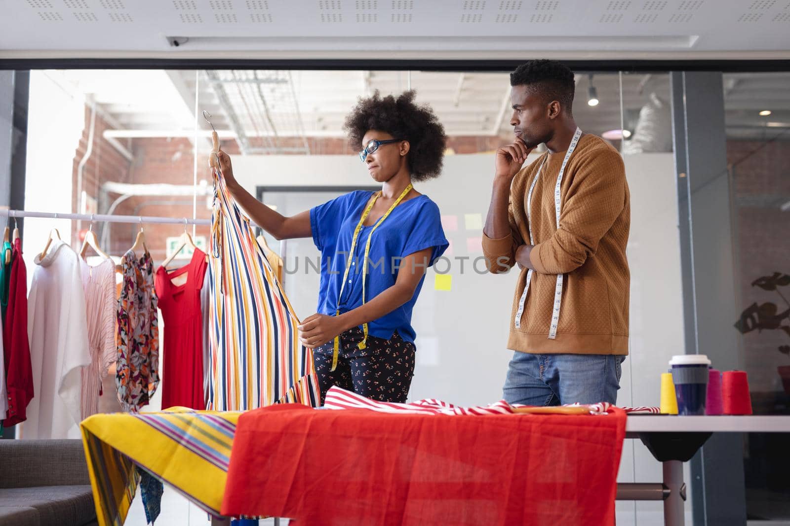 Diverse male and female fashion designers at work discussing and looking at fabric. independent creative design business.