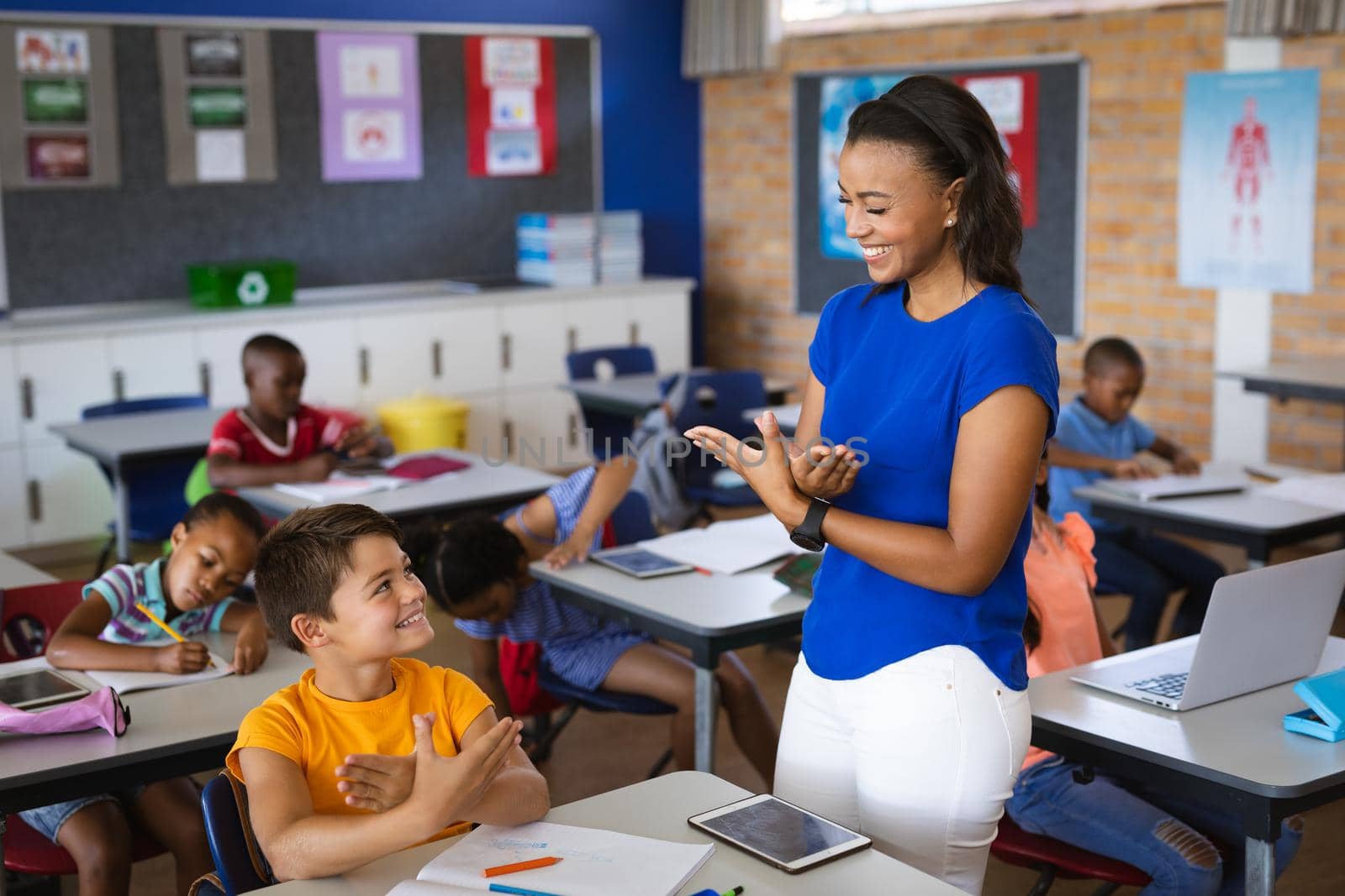 African american female teacher and caucasian boy talking in hand sign language at elementary school. school and education concept