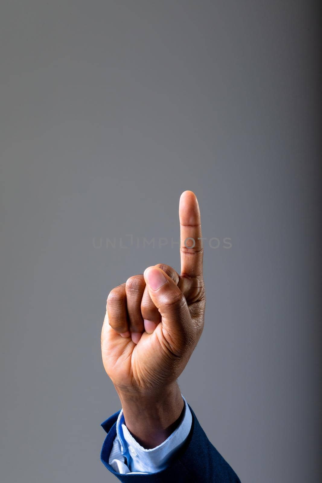 Close up of hand of businessman touching invisible screen against grey background by Wavebreakmedia