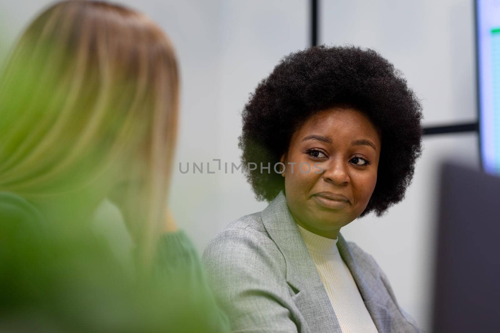 African american businesswoman in discussion at work smiling to business colleague by Wavebreakmedia