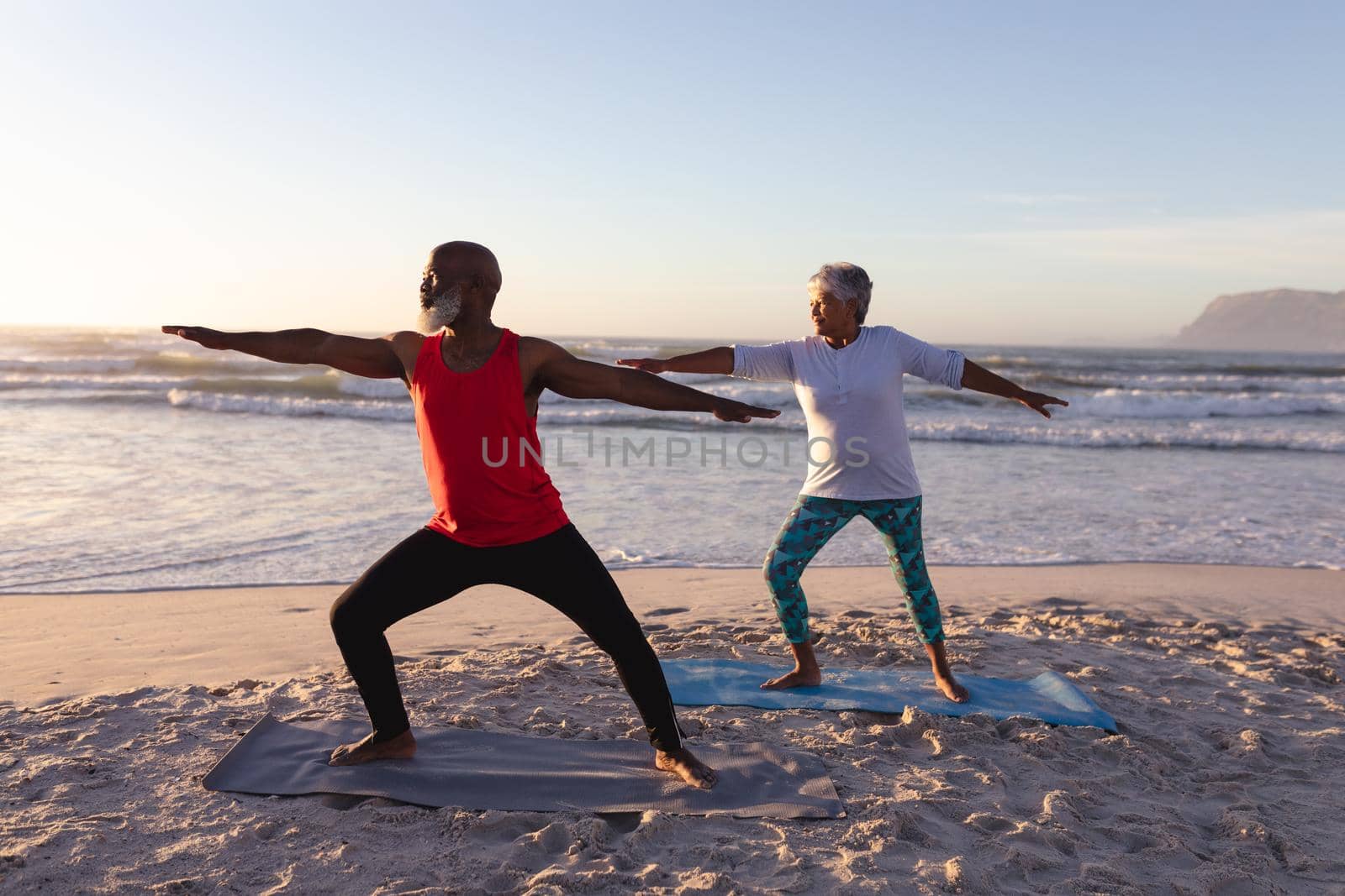 Senior african american couple performing stretching exercise together at the beach by Wavebreakmedia