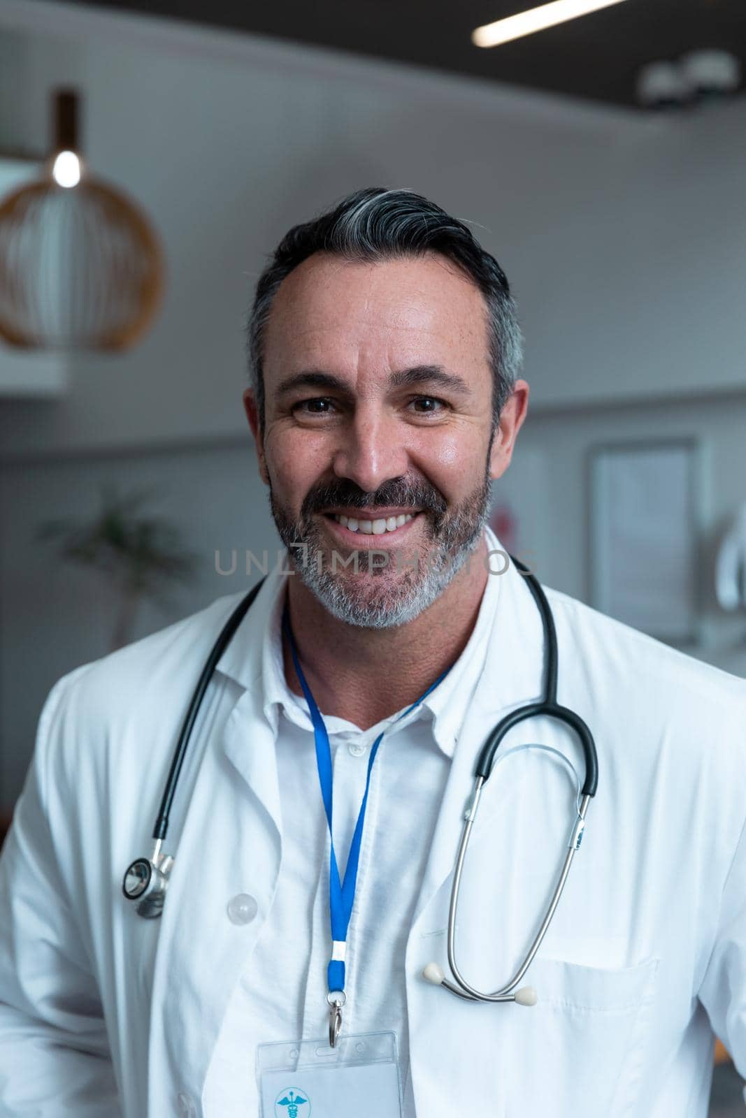 Portrait of smiling caucasian male doctor with stethoscope wearing lab coat in hospital by Wavebreakmedia