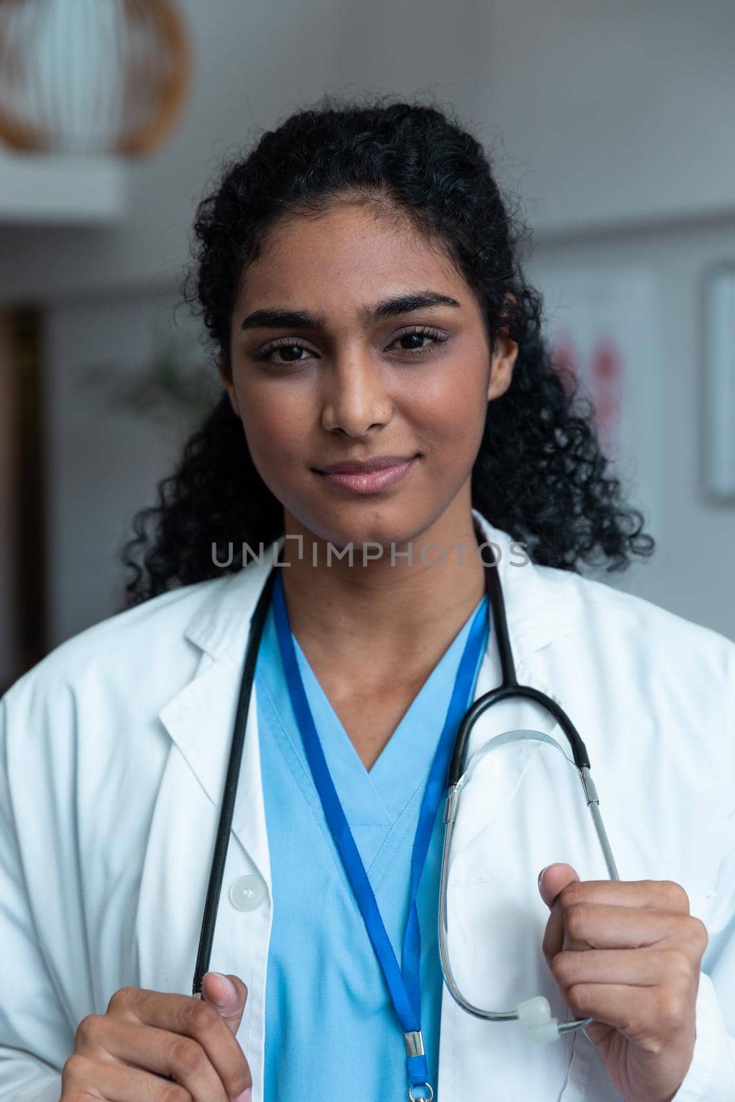Portrait of smiling mixed race female doctor with stethoscope wearing lab coat in hospital by Wavebreakmedia