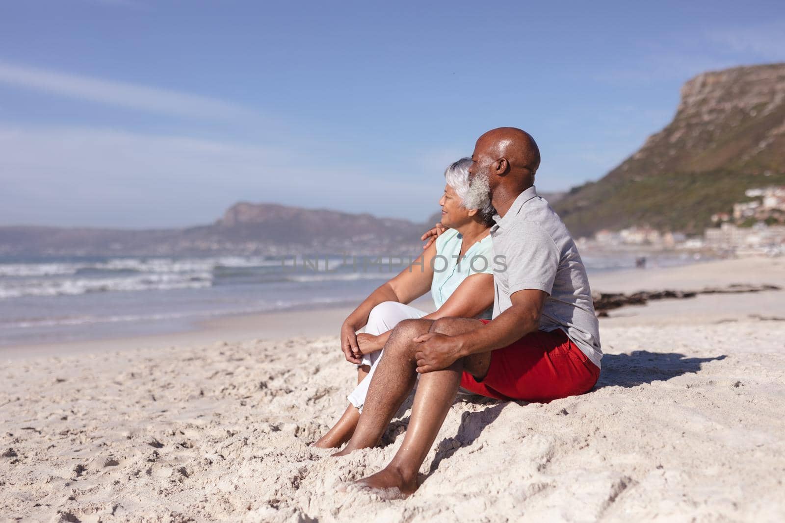 Happy senior african american couple sitting together on the beach. travel vacation retirement lifestyle concept