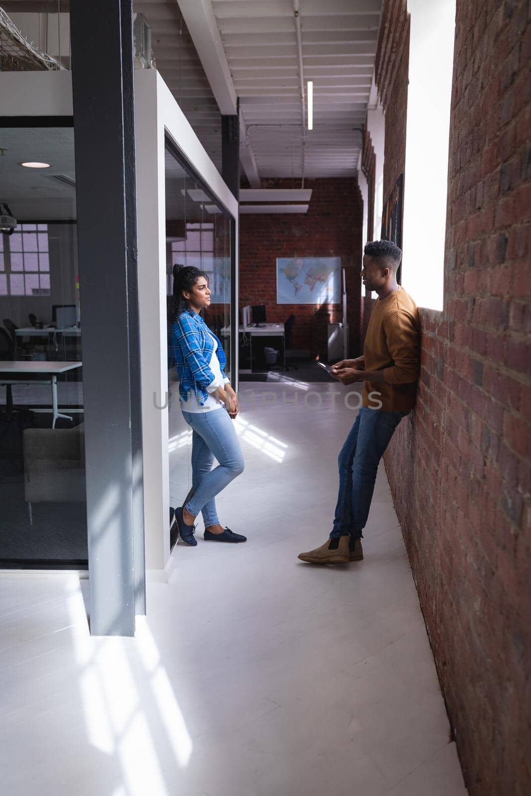 Diverse male and female colleagues at work standing discussing in corridor by Wavebreakmedia