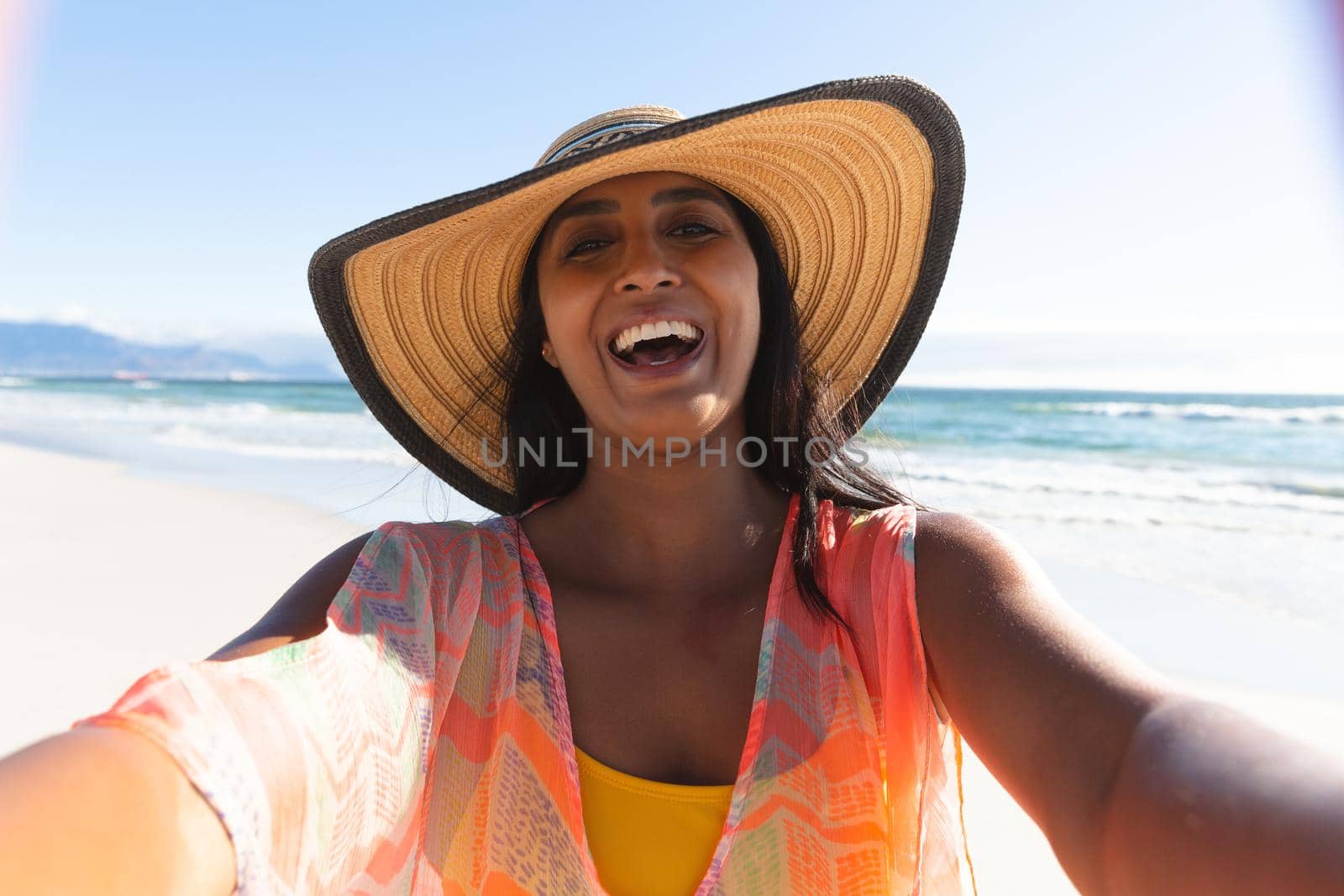 Happy mixed race woman on beach holiday taking selfie. outdoor leisure vacation time by the sea.