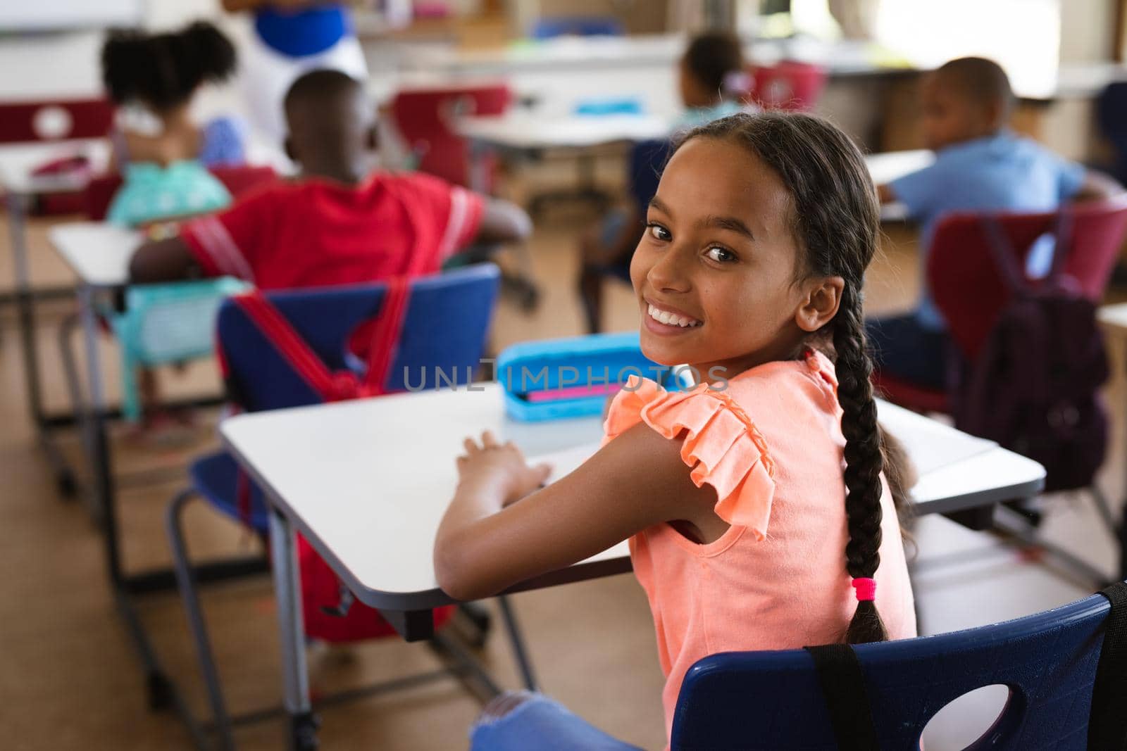 Portrait of african american girl smiling while sitting in the class at elementary school. school and education concept