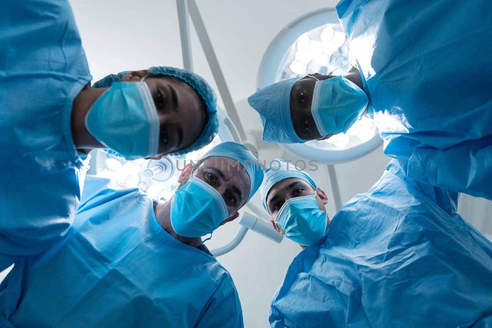 Diverse surgeons wearing face masks and protective clothing in operating theatre. medicine, health and healthcare services during covid 19 coronavirus pandemic.