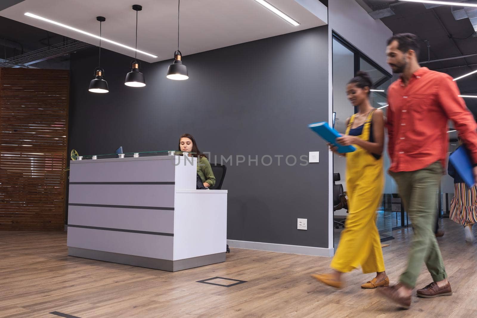 Two diverse creative colleagues walking holding documents and smiling. modern office of a creative design business.