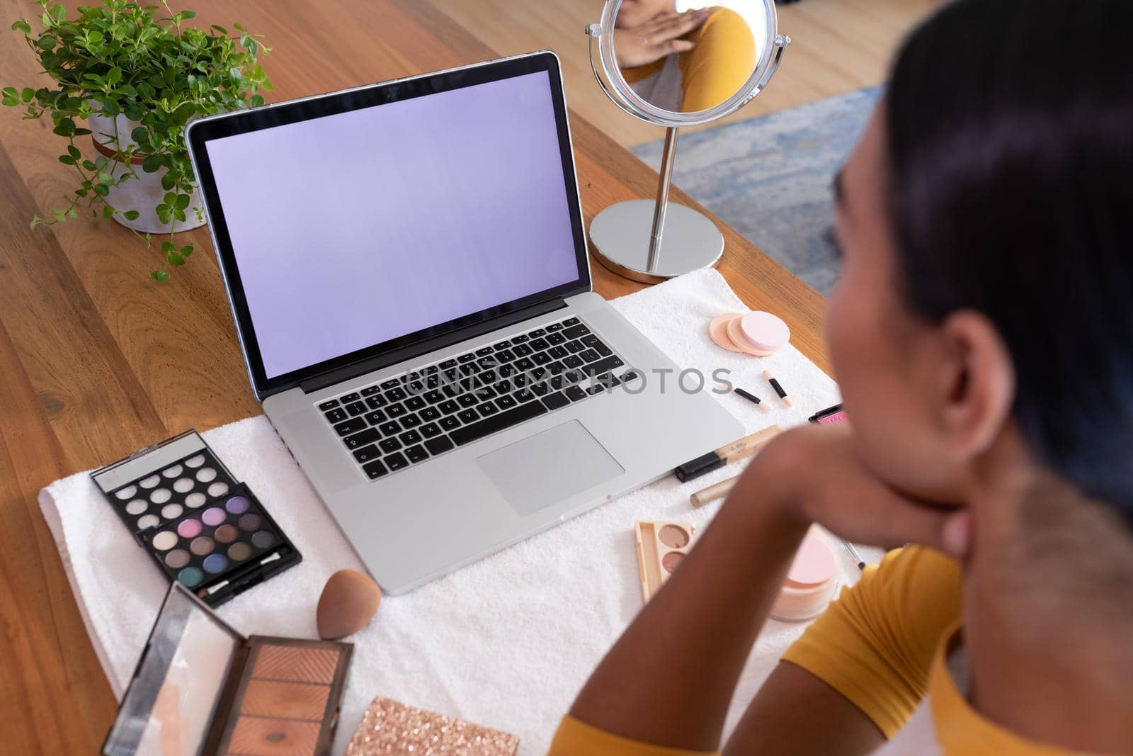 Mixed race gender fluid man making makeup vlog using laptop with copy space screen. staying at home in isolation during quarantine lockdown.