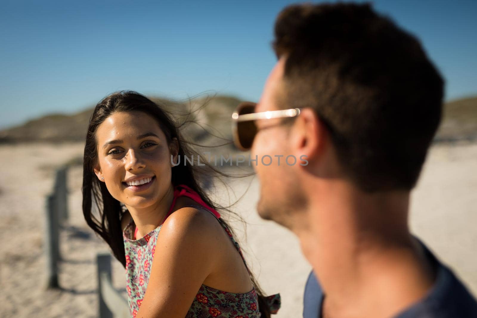 Happy caucasian couple sitting on beach by the sea woman looking to camera by Wavebreakmedia