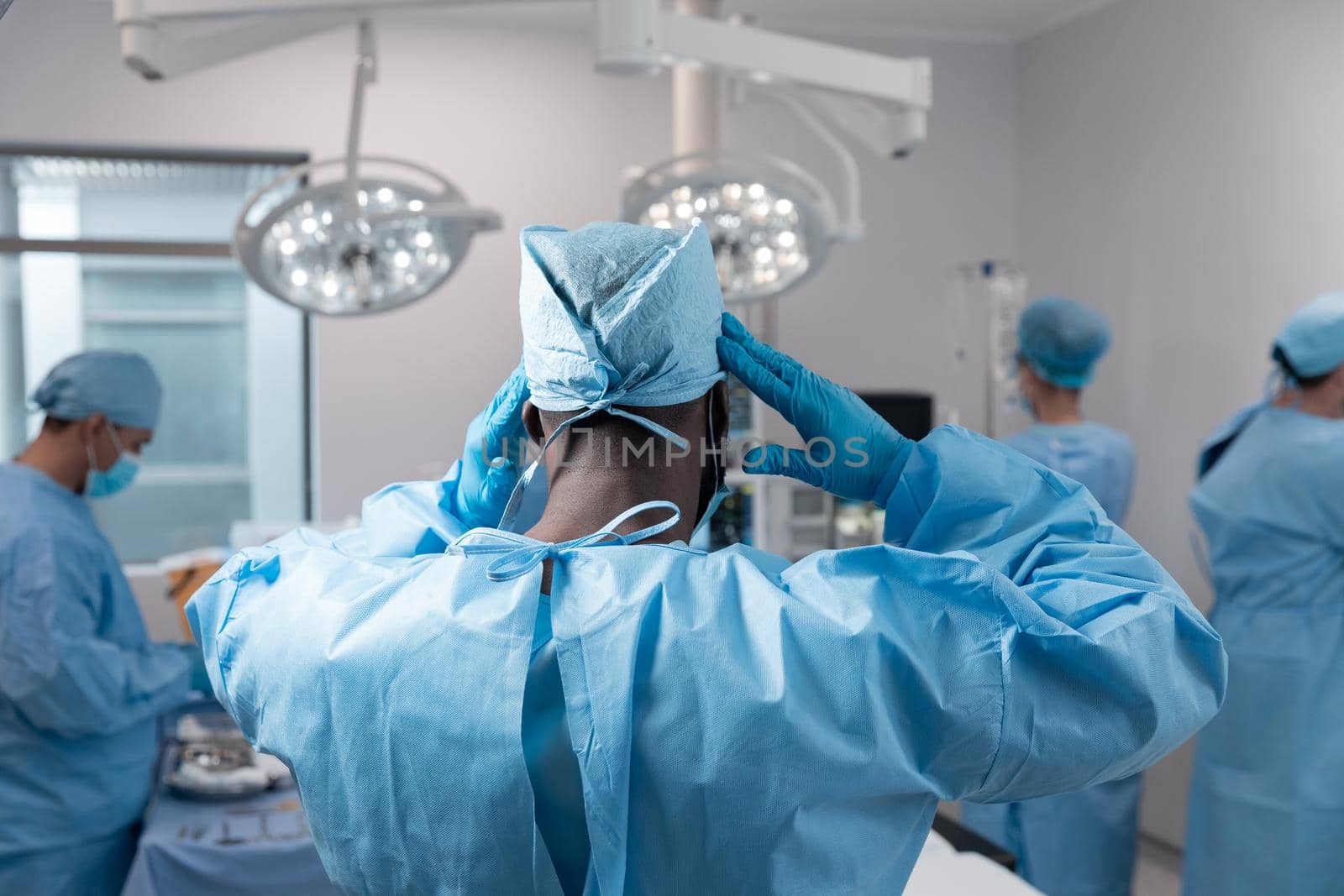 Mixed race doctors wearing face masks and surgical overalls standing in operating theatre. medicine, health and healthcare services during coronavirus covid 19 pandemic.
