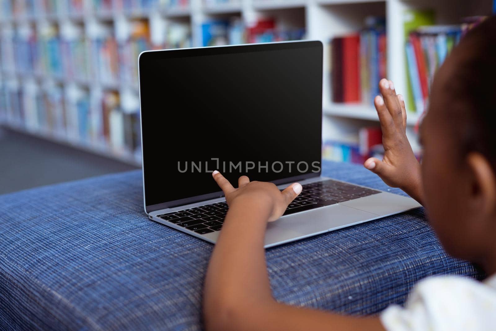 African american schoolgirl at desk in school library using laptop, with copy space on screen by Wavebreakmedia