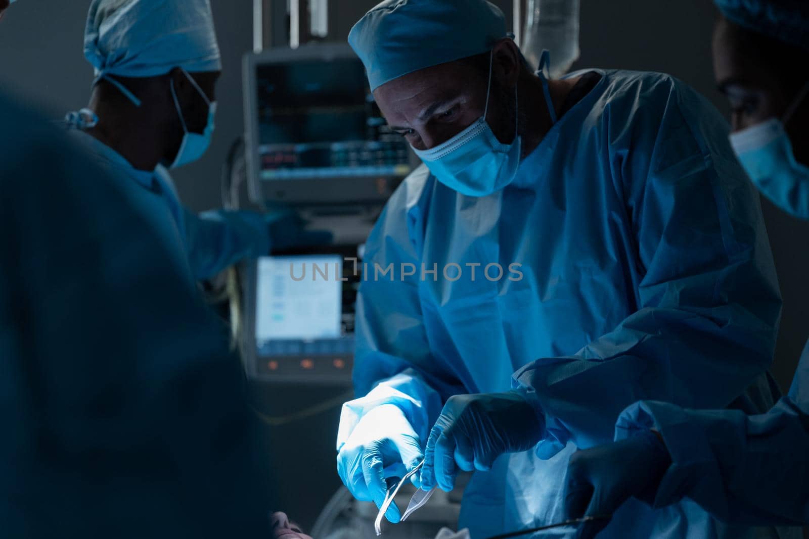 Caucasian male surgeon wearing face mask and protective clothing during operation in hospital. operating theatre. medicine, health and healthcare services during covid 19 coronavirus pandemic.