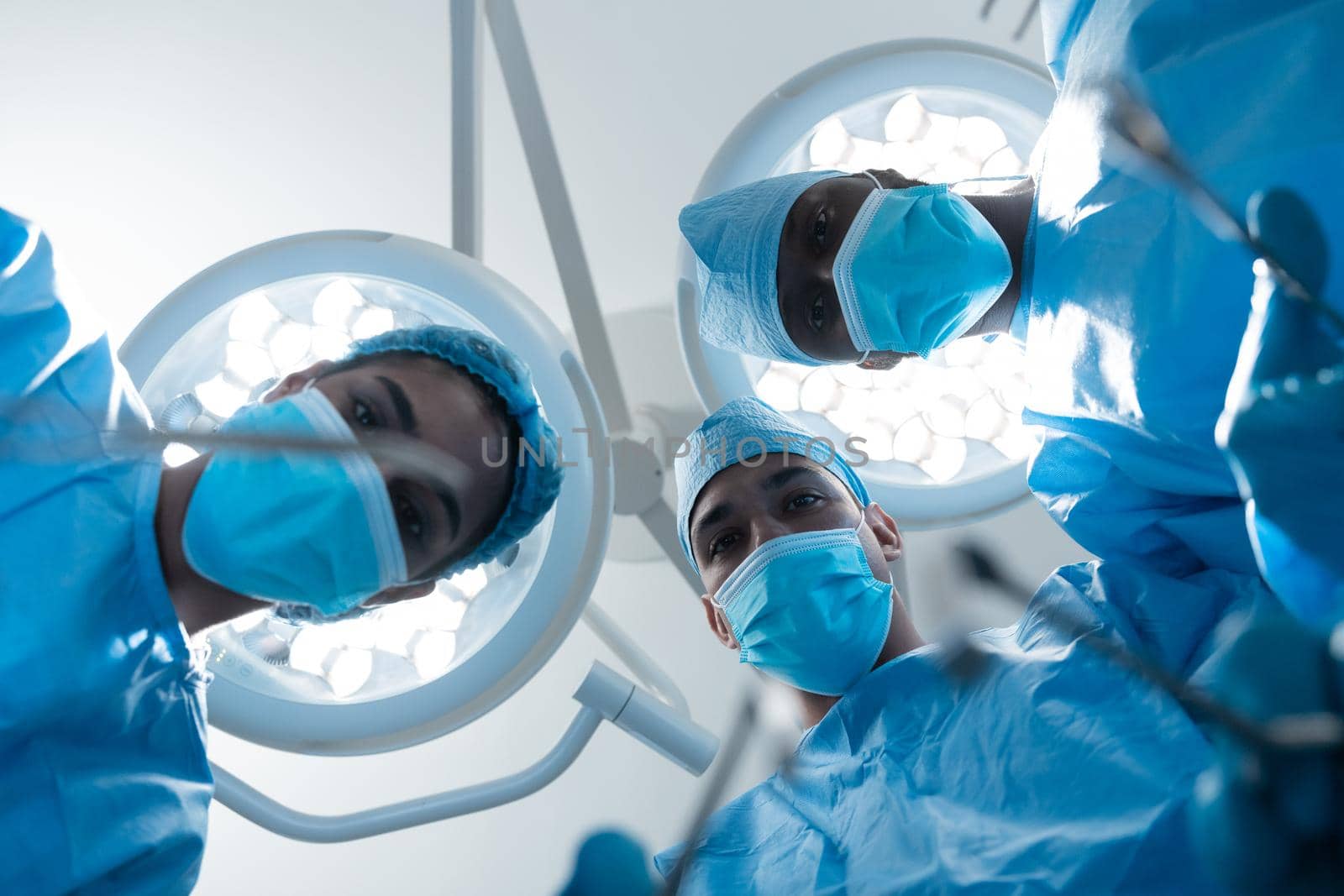 Diverse surgeons wearing face masks and protective clothing in operating theatre. medicine, health and healthcare services during covid 19 coronavirus pandemic.