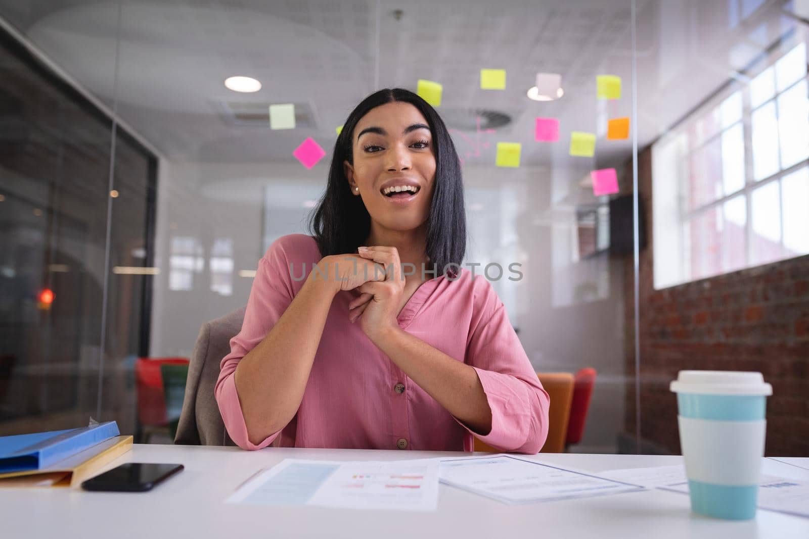 Happy mixed race businesswoman sitting at desk while having a video call smiling. independent creative design business.