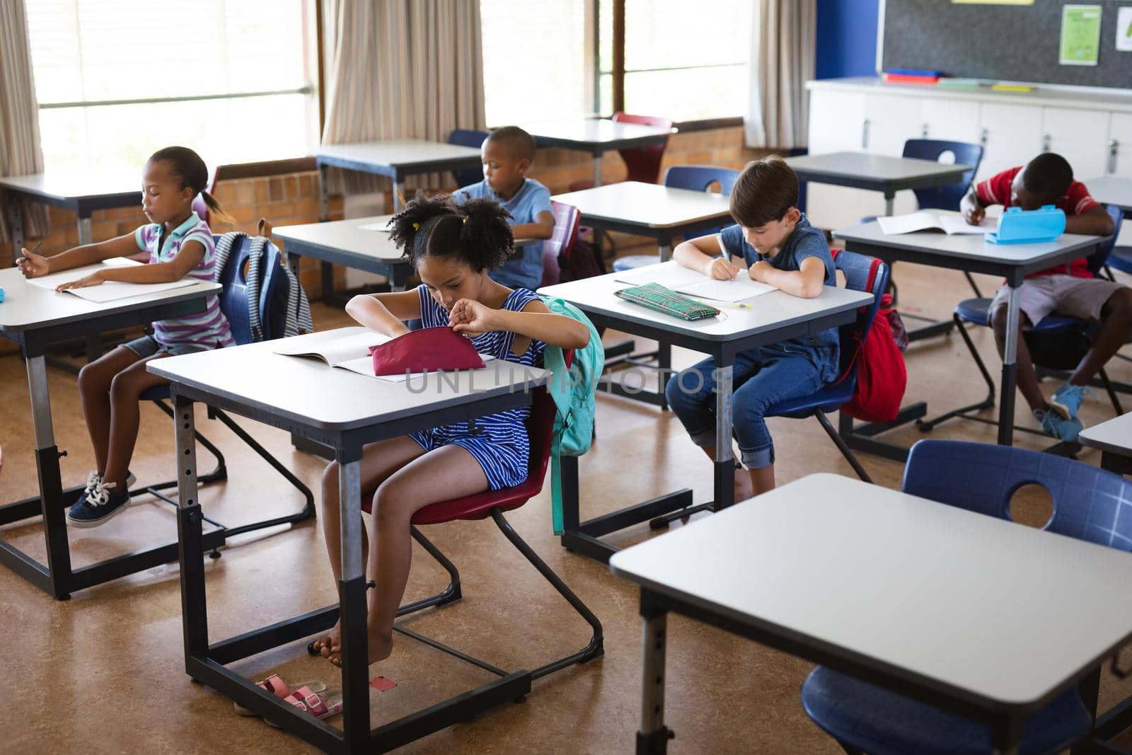 Group of diverse students studying while sitting on their desks in the class at school. school and education concept