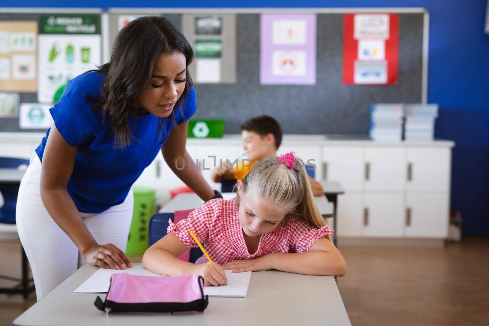 African american female teacher teaching caucasian girl in the class at elementary school. school and education concept