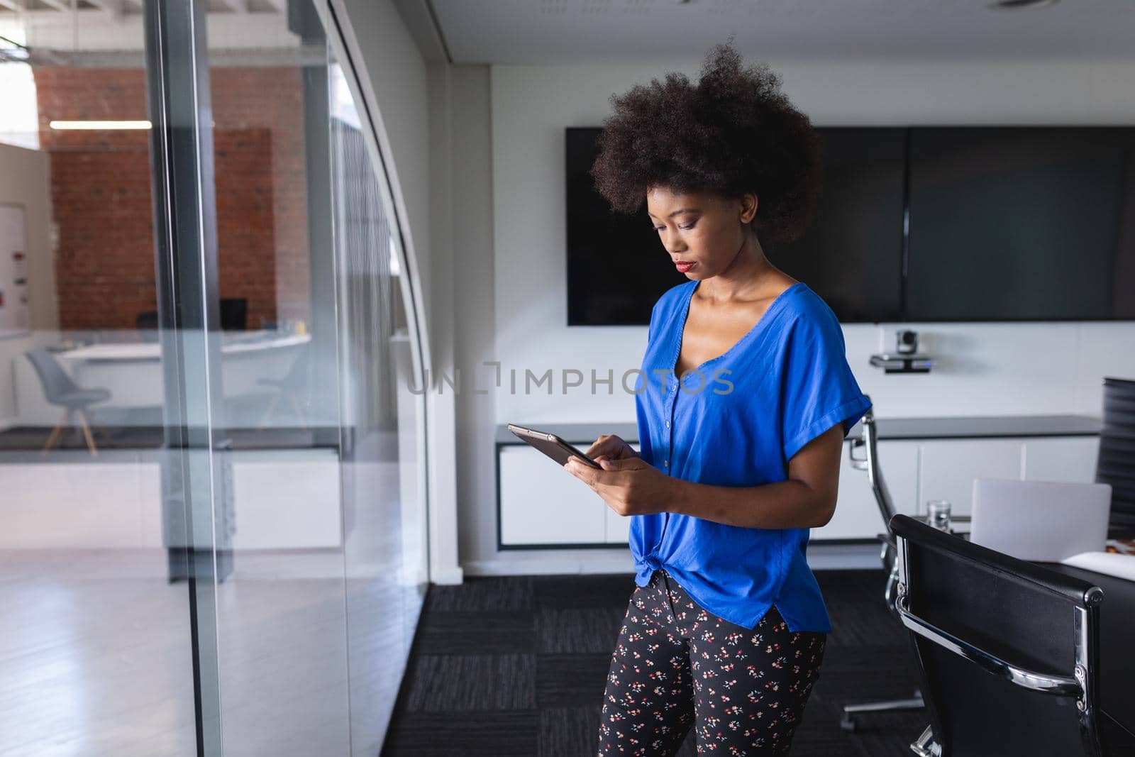 African american business woman in meeting room standing and using tablet. independent creative design business.