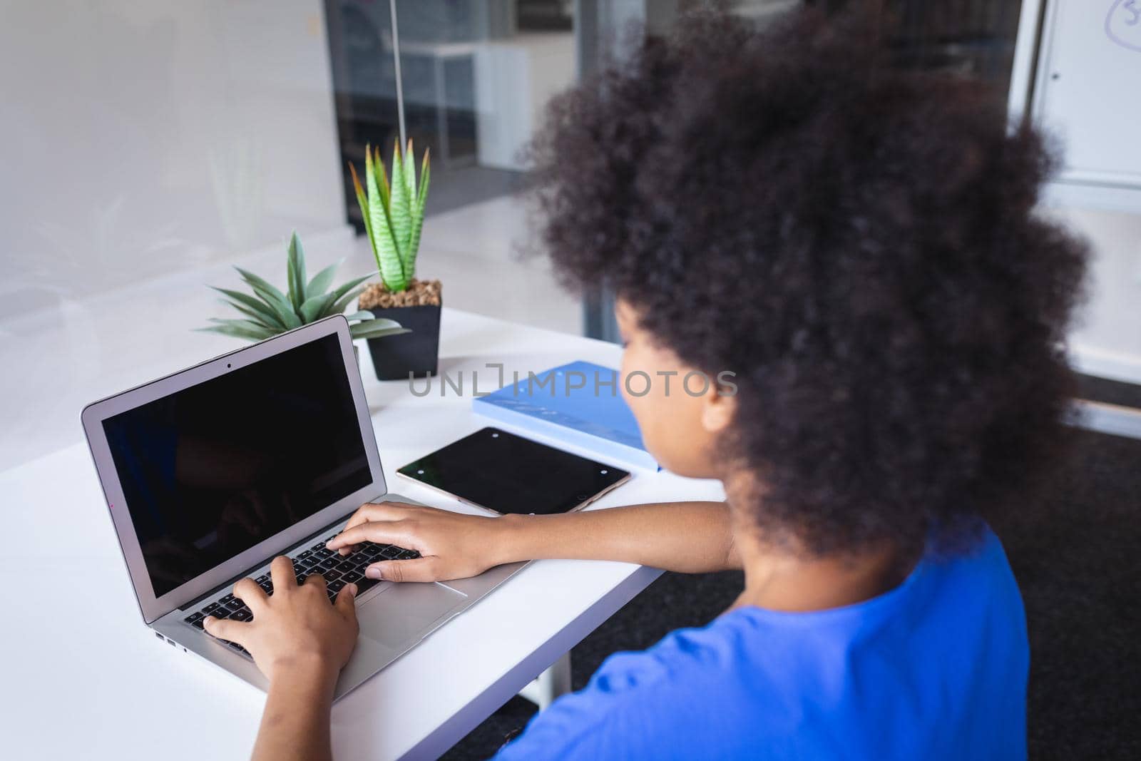 Mixed race businesswoman sitting in office in front of computer with blank screen by Wavebreakmedia