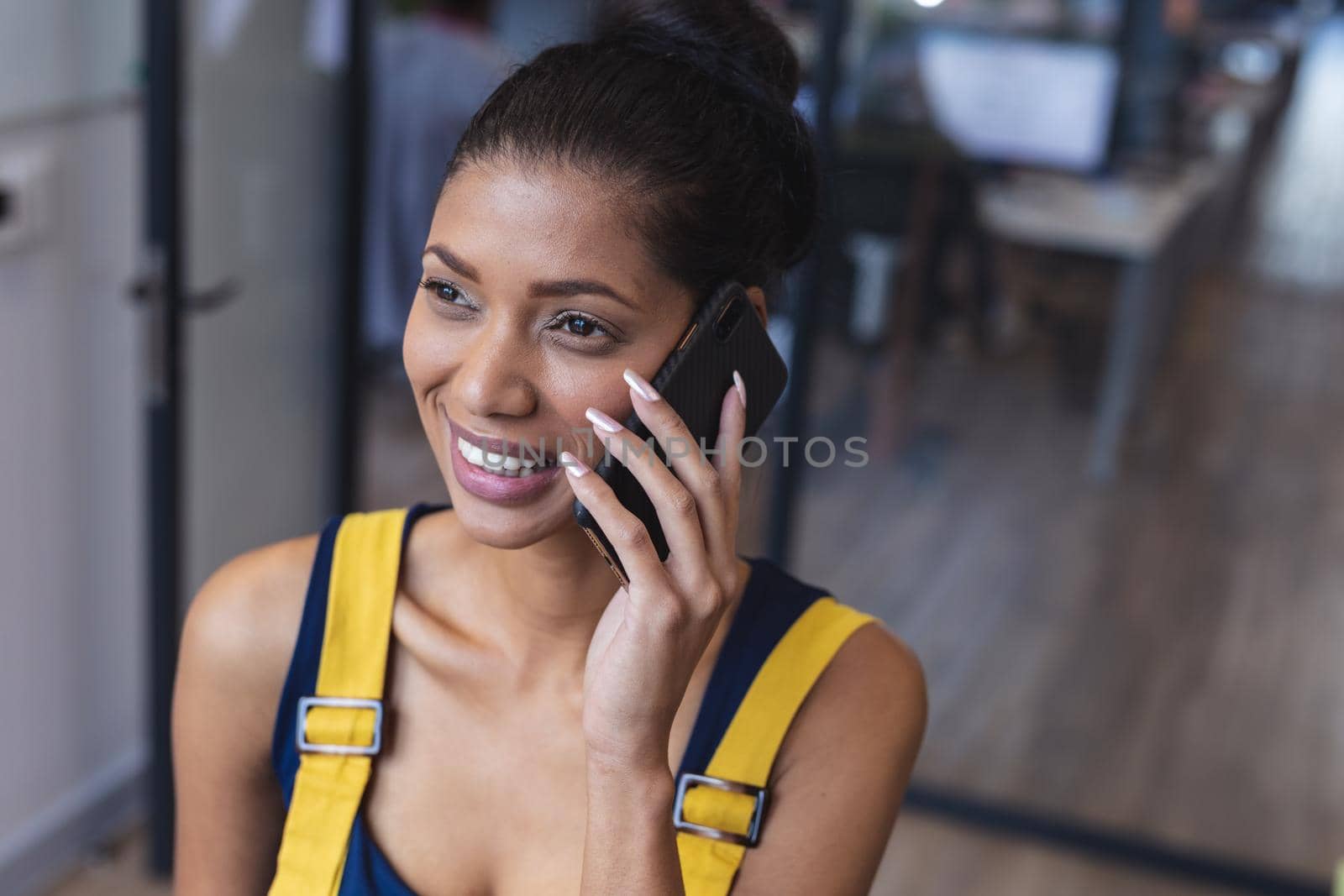 Mixed race female creative worker talking on smartphone and smiling by Wavebreakmedia