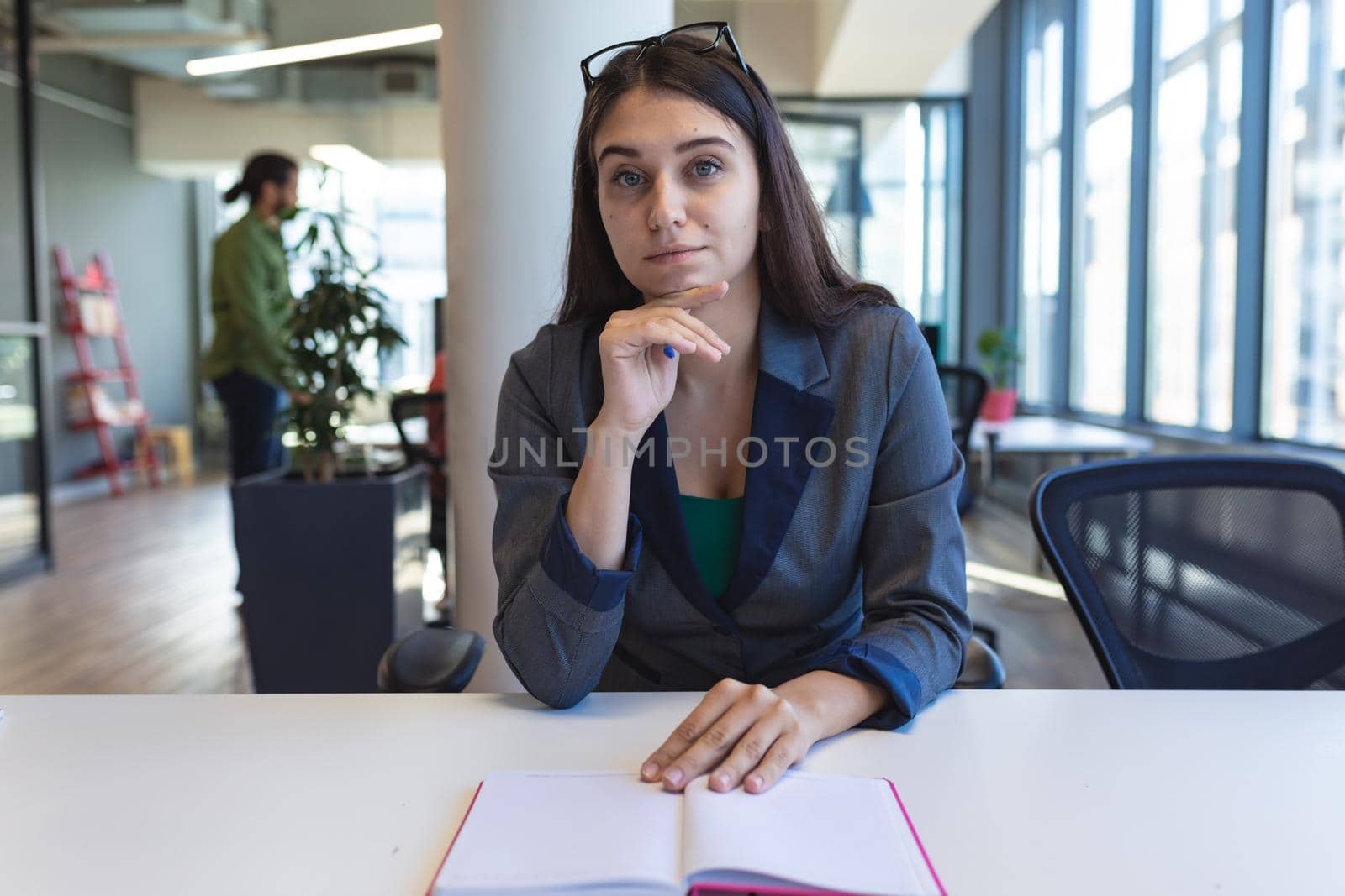 Portrait of caucasian female creative worker sitting at desk looking at camera. modern office of a creative design business.