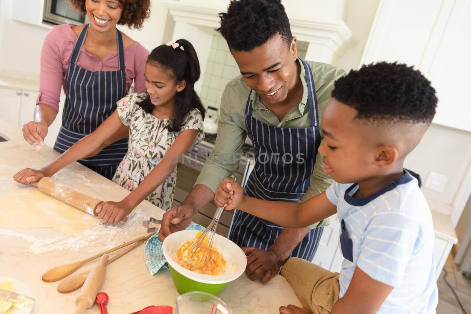 Happy african american parents baking with son and daughter in kitchen. family enjoying quality free time together.