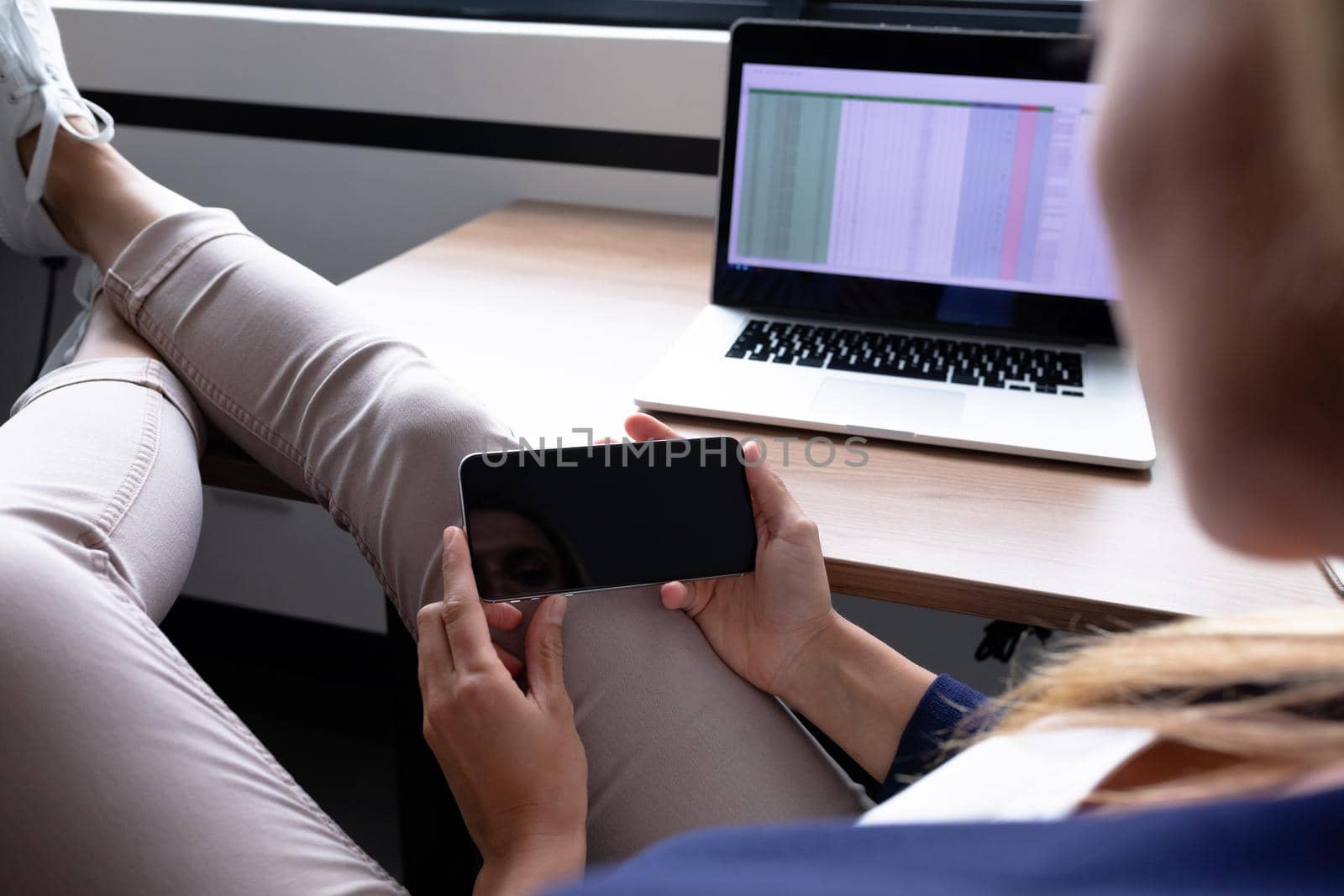 Caucasian businesswoman sitting at desk having video call conversation using smartphone by Wavebreakmedia