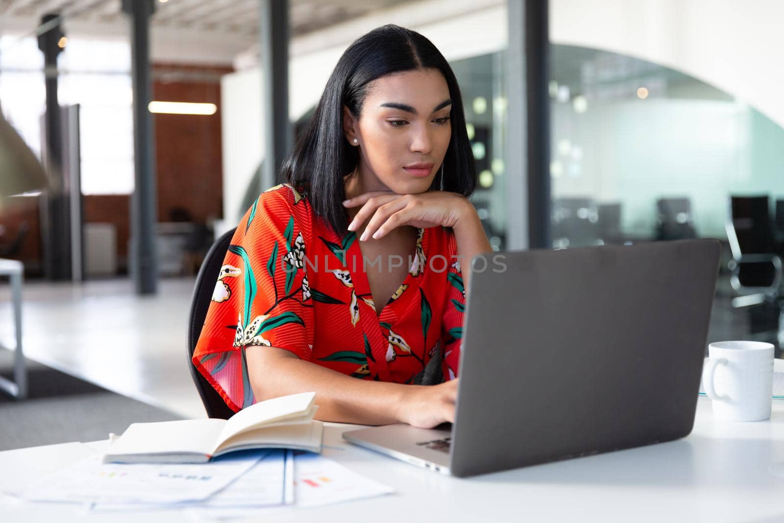 Portrait of mixed race businesswoman sitting in front of laptop working by Wavebreakmedia