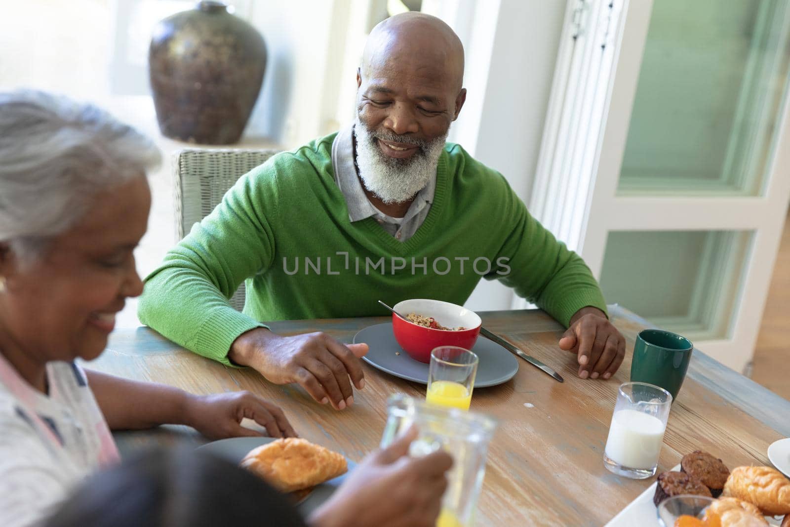 Happy african american family sitting at table smiling during breakfast and smiling. family enjoying quality free time together.