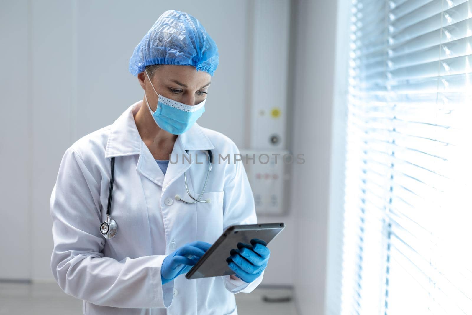 Caucasian female doctor wearing mask and latex gloves using tablet. medicine, health and healthcare services during coronavirus covid 19 pandemic.