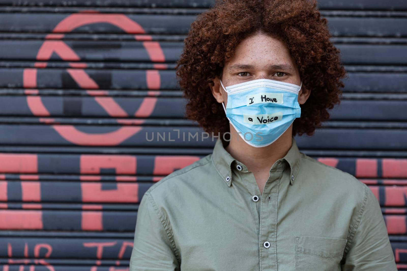 Portrait of mixed race man wearing a face mask with writing. equal rights and justice protestors on demonstration march during coronavirus covid 19 pandemic.