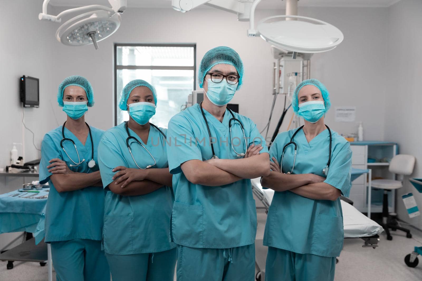 Diverse group of male and female doctors standing in operating theatre wearing face masks by Wavebreakmedia