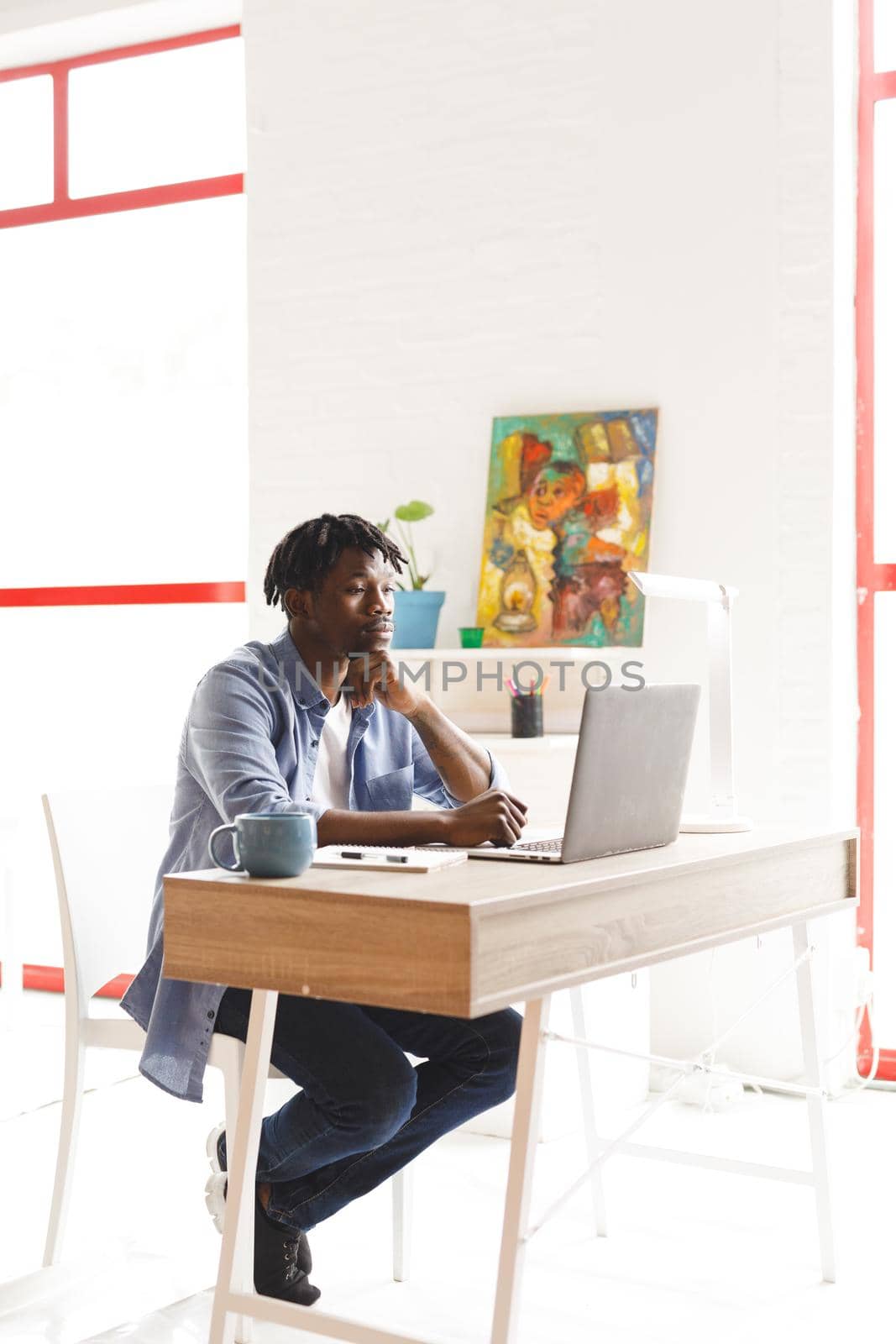 African american male painter at work using laptop in art studio. creation and inspiration at an artists painting studio.