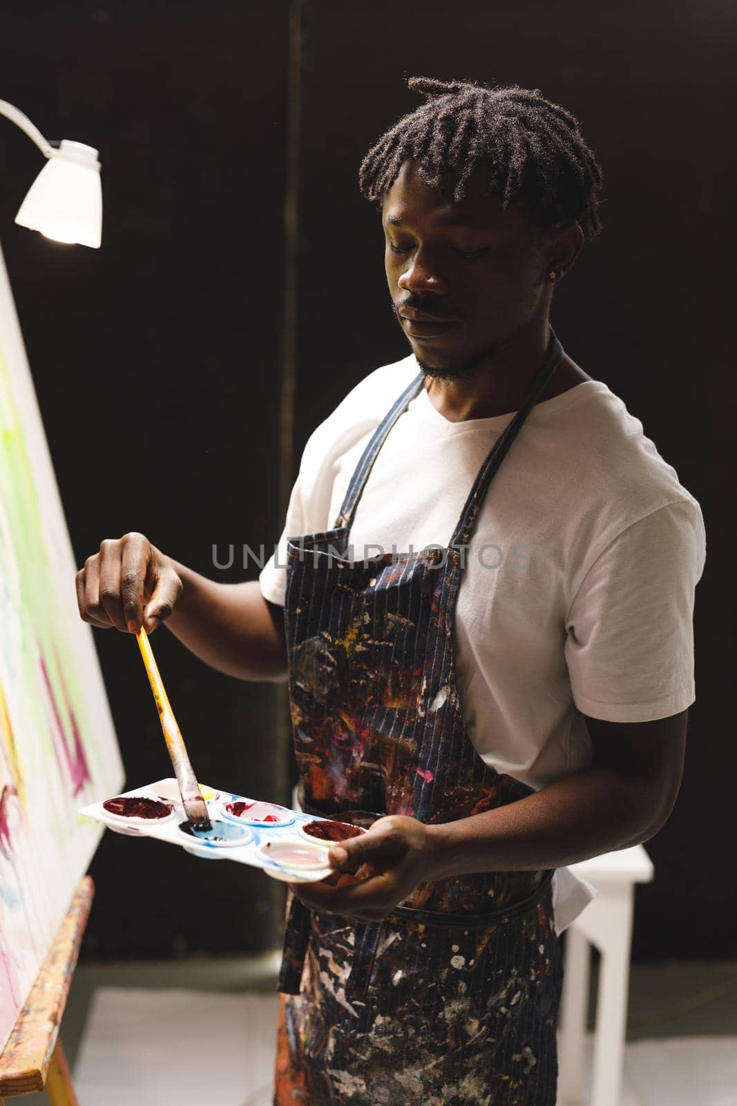 African american male painter at work painting on canvas in art studio. creation and inspiration at an artists painting studio.