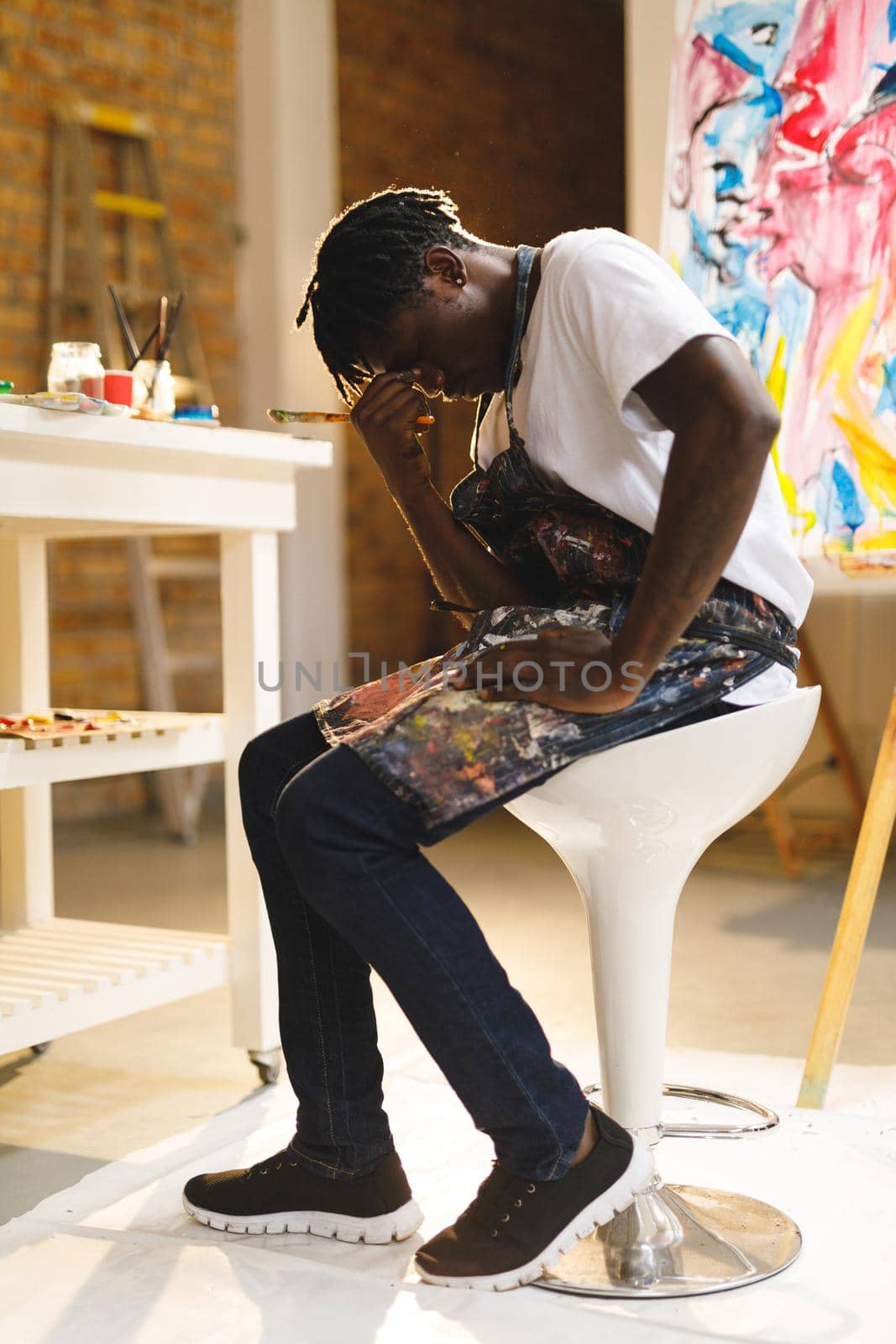 Tired african american male painter at work in art studio. creation and inspiration at an artists painting studio.